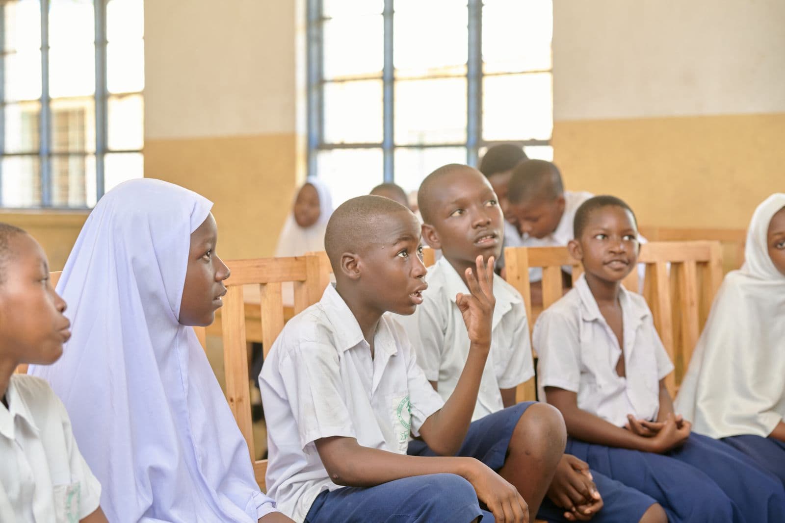 Students in a Jenga club classroom, one raising a hand