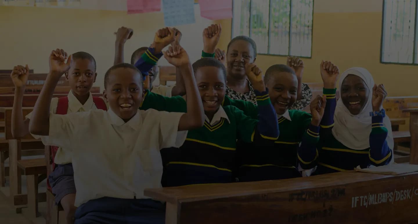 Students cheering at their desks in a Tanzanian classroom